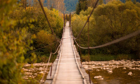 Landscape view of long wooden suspension bridge over mountains riverの写真素材