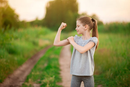 Child cute girl show biceps gesture of power and strength outdoor. Feel so powerful. Girls rules...