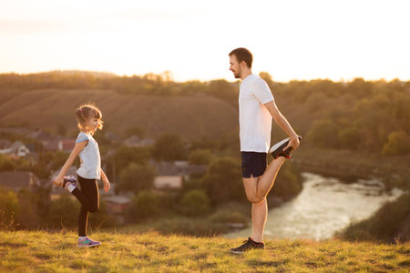 Father and cute daughter doing yoga outside in bright sunny day, lovely emotions. together at park....