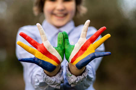 Freedom Seychelles concept. Cute child forming flying bird gesture with hands painted in Seychelles flag colors. Focus on handsの写真素材