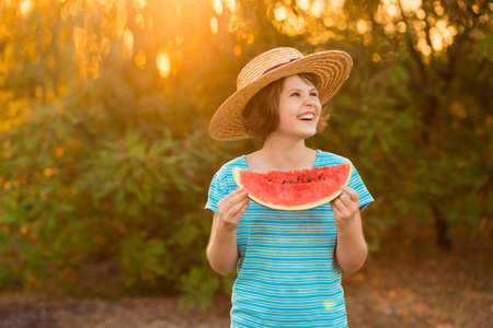 Adorable little preschool kid boy with blond hairs eating watermelon in summer holidays outdoor. Funny happy child smiling and tasting healthy fruit snack on sunny day.の写真素材