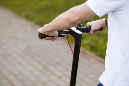 Man hands hold steering wheel of electric scooter outdoor and ready to goの写真素材