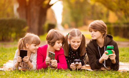 Smartphone addiction group of little children watching film movie cartoon together on digital tablet. Kids playing with phone togetherの写真素材