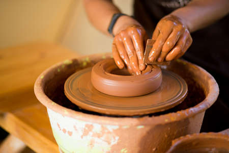 Man potter work with clay ware. Young handsome man potter on his workshop.の写真素材