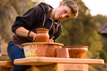Man potter work with clay ware. Young handsome man potter on his workshop.の写真素材