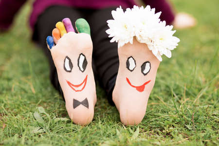 Images of lovely groom and bride just married painted in bright colors on feet of child outdoor at summer. Thinking outside the boxの写真素材