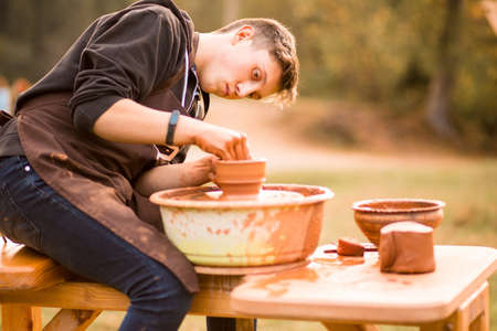 Man potter work with clay ware. Young handsome man potter on his workshop.の写真素材