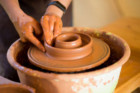 Man potter work with clay ware. Young handsome man potter on his workshop.の写真素材