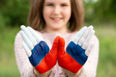 Child girl show hands painted in Russia flag colors walking outdoor, focus on hands. Day of Russian flag. Patriots patriotism citizens nationality. June 12. August 22 holiday. November 4の写真素材