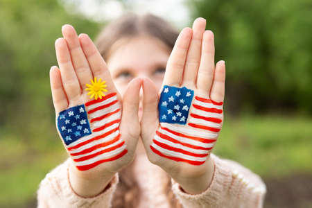 Cute little child girl with painted hands in American flag color, focus on hands. USA celebrate 4th of July. Independence Day, memorial day, flag day June 14の写真素材