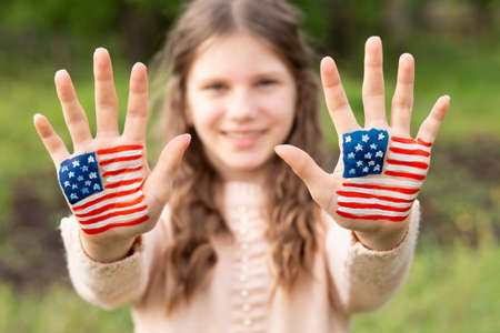 Cute little child girl with painted hands in American flag color, focus on hands. USA celebrate 4th of July. Independence Day, memorial day, flag day June 14の写真素材