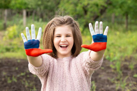 Child girl show hands painted in Russia flag colors walking outdoor. Day of Russian flag. Patriots patriotism citizens nationality. June 12. August 22 holiday. November 4の写真素材