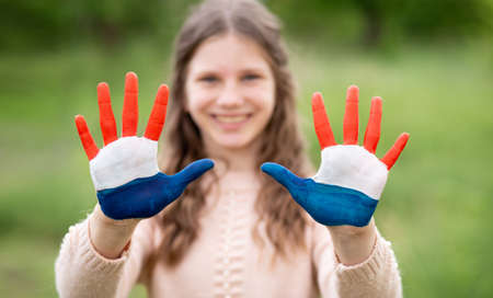 Croatia flag painted on child hands. Girl with open hands raised, focus on hands. Patriotic holiday. Independence Day, 25 June. Selective focus. Croatia Independence Day concept. Victory and Homeland Thanksgiving Day, 5 August, 15 August. Green grass background.の写真素材