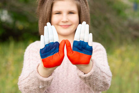 Child girl show hands painted in Russia flag colors walking outdoor, focus on hands. Day of Russian flag. Patriots patriotism citizens nationality. June 12. August 22 holiday. November 4の写真素材