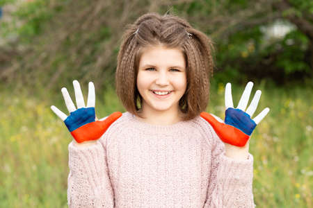 Child girl show hands painted in Russia flag colors walking outdoor. Day of Russian flag. Patriots patriotism citizens nationality. June 12. August 22 holiday. November 4の写真素材