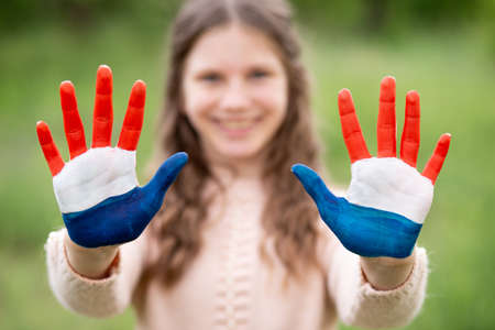 Croatia flag painted on child hands. Girl with open hands raised, focus on hands. Patriotic holiday. Independence Day, 25 June. Selective focus. Croatia Independence Day concept. Victory and Homeland Thanksgiving Day, 5 August, 15 August. Green grass background.の写真素材
