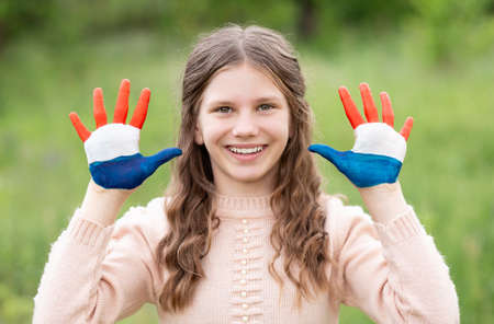 Croatia flag painted on child hands. Girl with open hands raised. Patriotic holiday. Independence Day, 25 June. Croatia Independence Day concept. Victory and Homeland Thanksgiving Day, 5 August, 15 August. Green grass background.の写真素材
