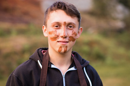 Joyful portrait of man potter with clay dirty face. Young handsome man on pottery workshop of ceramic for children. Hobby and leisure conceptの写真素材
