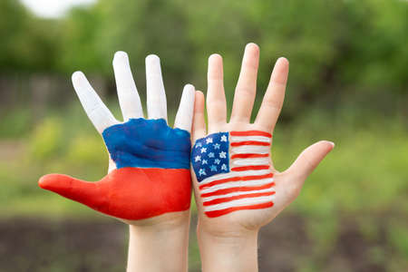 Friendship of peoples, exchange of students. Learning foreign languages. Child hands painted in American and Russian flag color. Relations between Russia and the United States. Concept of friendship relations between Russia and USA.の写真素材