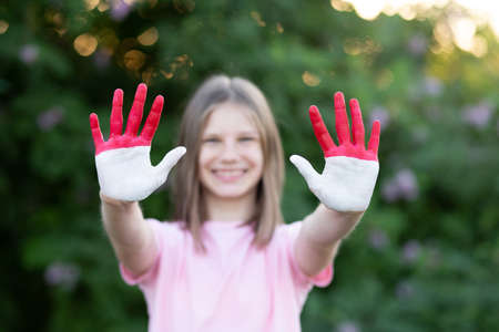 Child girl show hands painted in Indonesia and Monaco flag colors, focus on hands. Indonesian patriotism concept. Indonesian Independence Day, Hari Kemerdekaan Indonesia, 17 August. National Day of Monaco 19 Novemberの写真素材