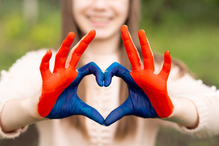 Love Mongolia concept. Little girl show hands in heart form painted in Mongolia flag color. Focus on hands. Mongolian patriotism. July 10 National Flag Day. Mongolian independence holiday 29th of December. January 13 Constitution Dayの写真素材