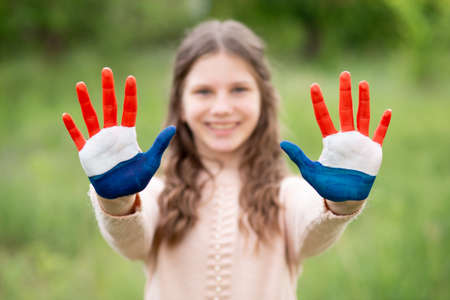 Croatia flag painted on child hands. Girl with open hands raised, focus on hands. Patriotic holiday. Independence Day, 25 June. Selective focus. Croatia Independence Day concept. Victory and Homeland Thanksgiving Day, 5 August, 15 August. Green grass background.の写真素材