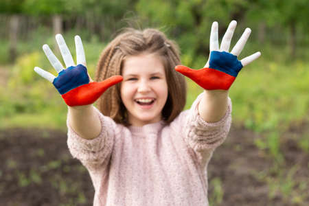 Child girl show hands painted in Russia flag colors walking outdoor, focus on hands. Day of Russian flag. Patriots patriotism citizens nationality. June 12. August 22 holiday. November 4の写真素材