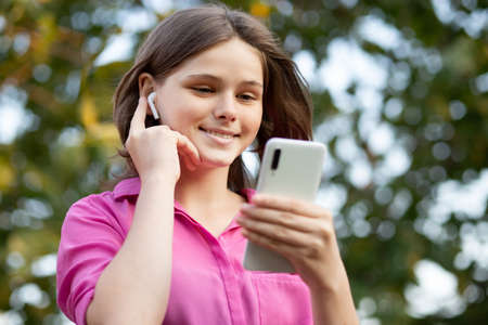 Overjoyed pretty girl wears in pink get carry away with music. Asian teenager girl use smartphone and enjoy favorite playlist via stereo headphones, relaxed sings along with carefree expression. High quality photoの写真素材