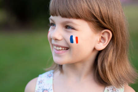 Portrait of child with painted French flag, closeup. Kid fan with blue white red flag painted on face. Education abroad. 14 July, Bastille day, main France national holidayの写真素材