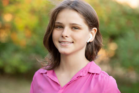 Beautiful young girl enjoy listening to music with wireless headphone with good mood and relax outdoor.の写真素材