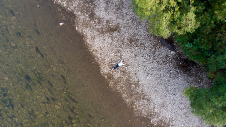 Aerial drone view from above of young woman lying on beach of sea. Space for text.の写真素材