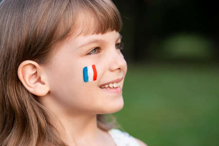 Portrait of child with painted French flag, closeup. Kid fan with blue white red flag painted on face. Education abroad. 14 July, Bastille day, main France national holidayの写真素材