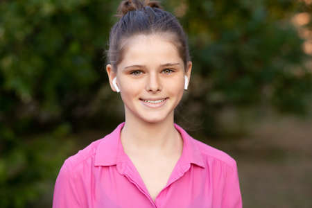Beautiful young girl enjoy listening to music with wireless headphone with good mood and relax outdoor.の写真素材