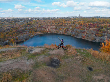 Young woman cycling on bike outdoors aerial view from above. Aerial view of happy sport girl relaxing near beautiful mountains lake from above, sport and fitness conceptの写真素材