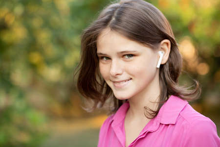 Beautiful young girl enjoy listening to music with wireless headphone with good mood and relax outdoor.の写真素材