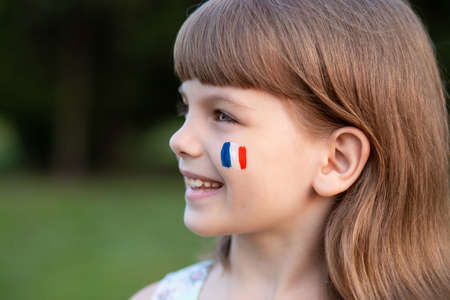 Portrait of child with painted French flag, closeup. Kid fan with blue white red flag painted on face. Education abroad. 14 July, Bastille day, main France national holidayの写真素材