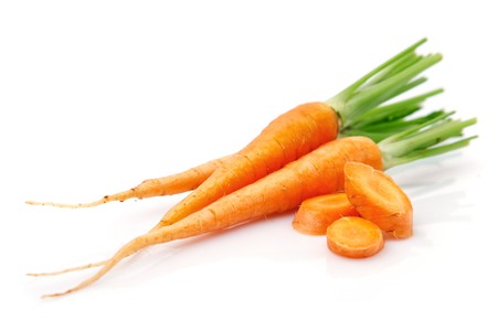 fresh carrot fruits with green leaves in the glass isolated on white backgroundの写真素材