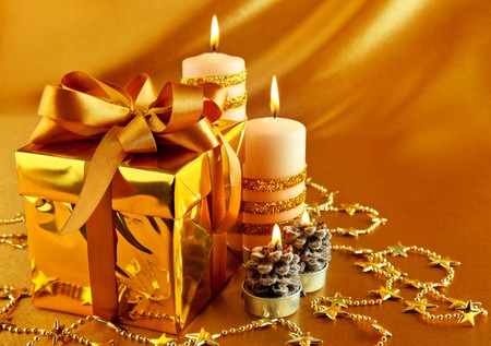 christmas gift in gold box with bow and candleの写真素材