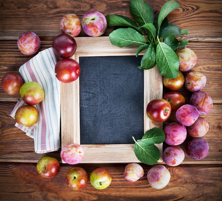Board for text with fresh plums and green leavesの写真素材