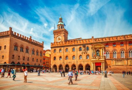 Italy Piazza Maggiore in Bologna old town tower of town hall with big clock and blue sky on background, antique buildings terracotta galleriesの写真素材