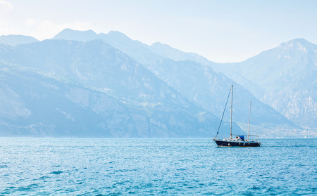 Sailer at water of lake or sea bay and high blue mountains in misty background landscapeの写真素材