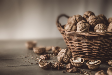 Walnut in wicker basket on old wooden board rustic style with nutshell top viewの写真素材