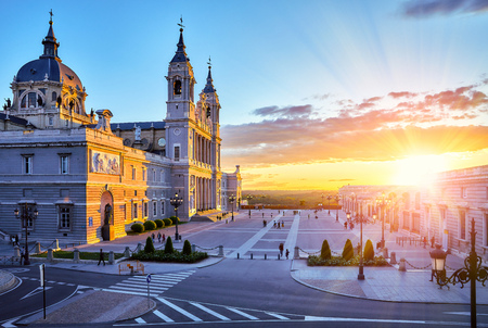 Madrid, Spain. Cathedral Santa Maria la Real de la Almudena at Plaza de la Armeria. Famous landmark with sunset sunand. Street lamps and picturesque sky with clouds.の写真素材