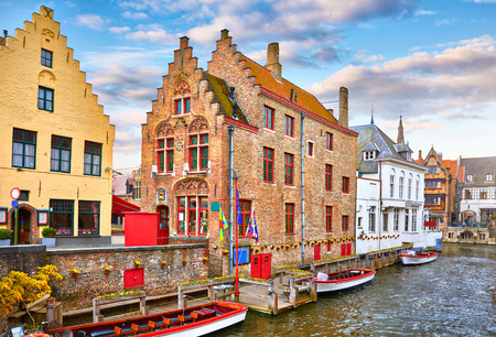 Bruges, Belgium. Medieval vintage brick houses with balconies over river with old bridge, covered with green plants and bushes.の写真素材