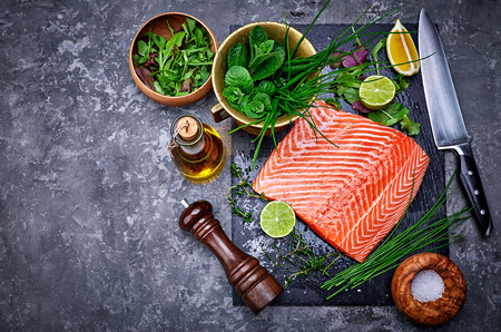 Fresh steak salmon red fish on black stone blackboard with knife cut lime and salt olive oil and spice.の写真素材