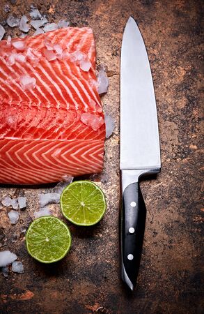 Fresh steak salmon red fish with ice on grunge background with knife and cuted lime top view.の写真素材