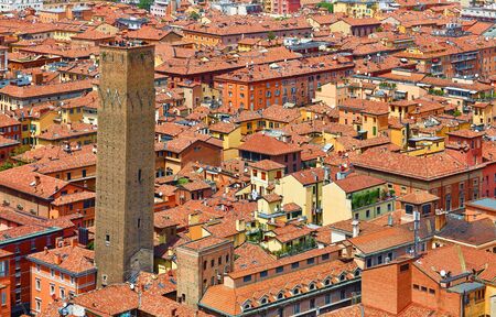 Bologna, Italy. Top view of old town with terracotta houses, street road, Prendiparte Tower and housetops. Sunny day urban italian landscape.の写真素材
