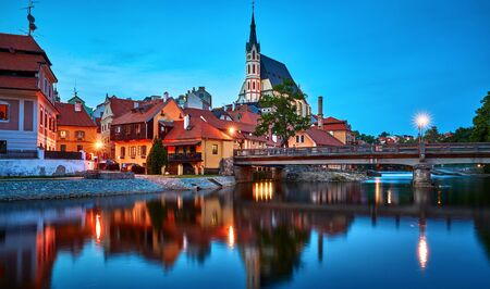 Czech Krumlov, Czech Republic. Evening view at bridge in old town with old houses and broach at tower of St. Vitus Church. Sunset blue hour with illuminationの写真素材