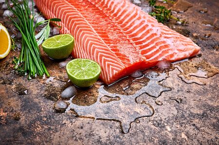 Fresh steak salmon red fish with ice on grunge with herbs and cut lime top view.の写真素材