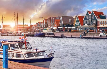 Volendam, Netherlands. Luxury yacht parked by pier in bay of North Sea on evening sunset under traditional old town.の写真素材
